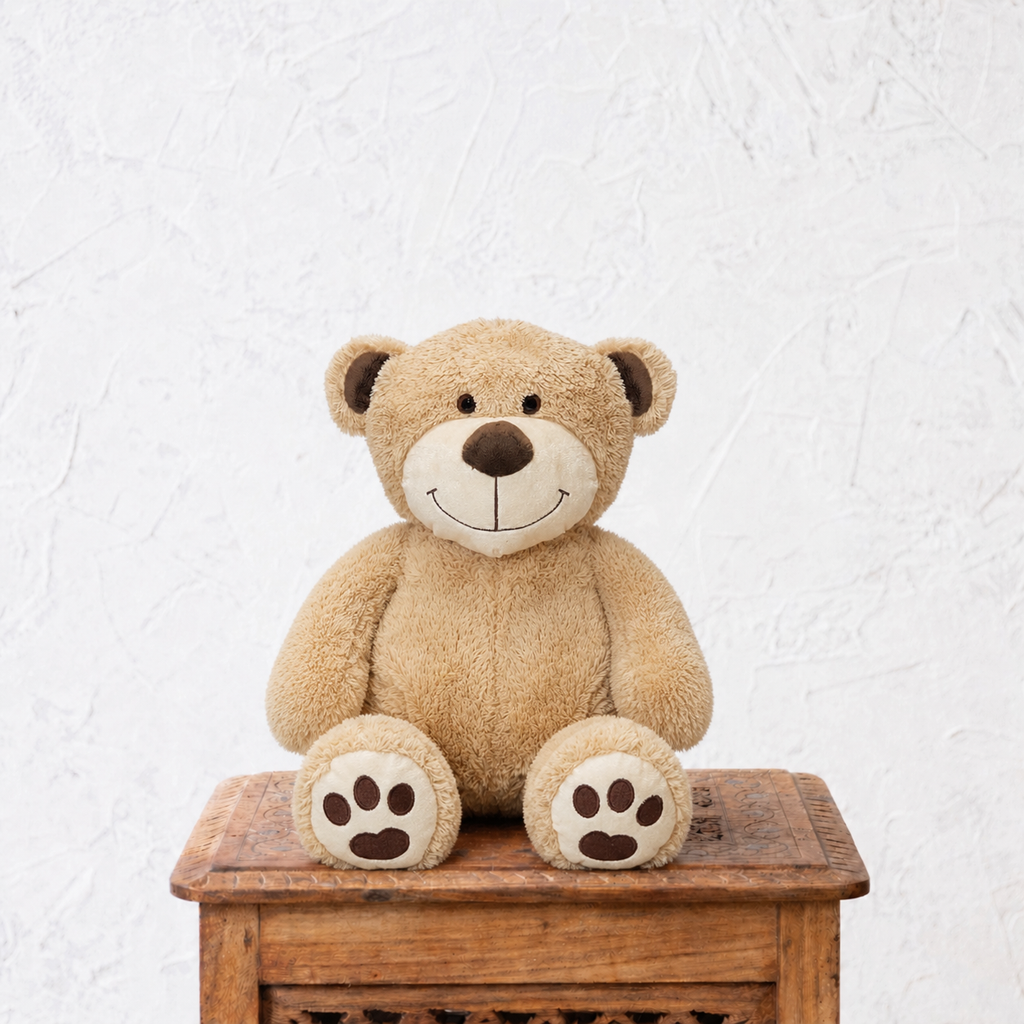 Brown teddy bear sitting on a wooden box against a white textured wall