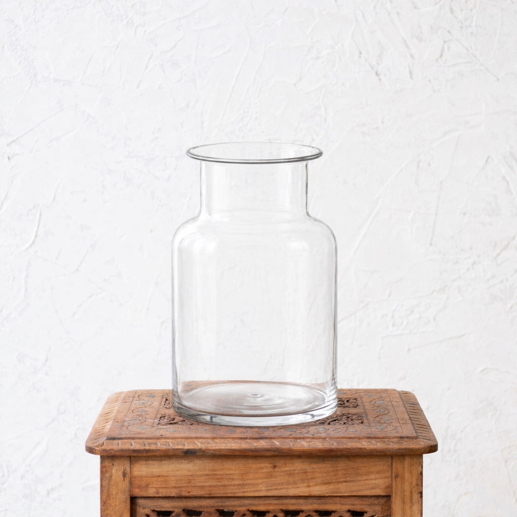 Clear glass vase on a wooden table with a white textured background