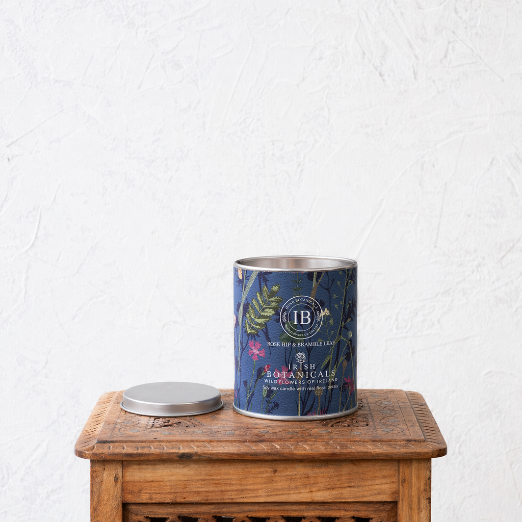 Tin canister with floral label on a wooden surface against a white wall