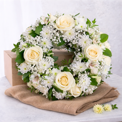 Floral wreath with white roses and greenery on a white background
