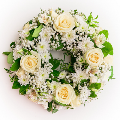 A white floral wreath arrangement with a variety of flowers, designed for sympathy purposes.