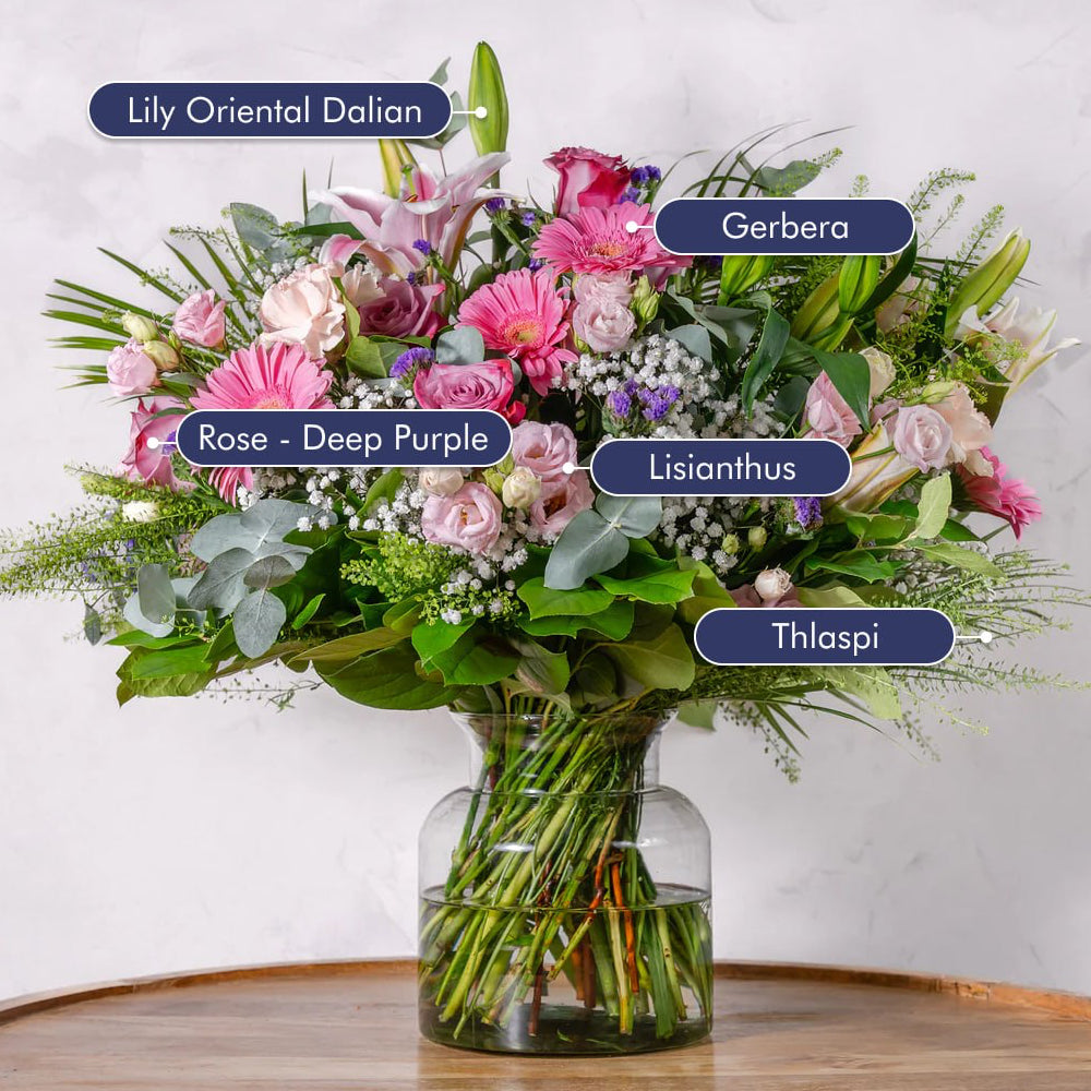 Soft pink and white premium bouquet placed on a surface as a gift, featuring roses, lilies and gerbera with trailing green eucalyptus