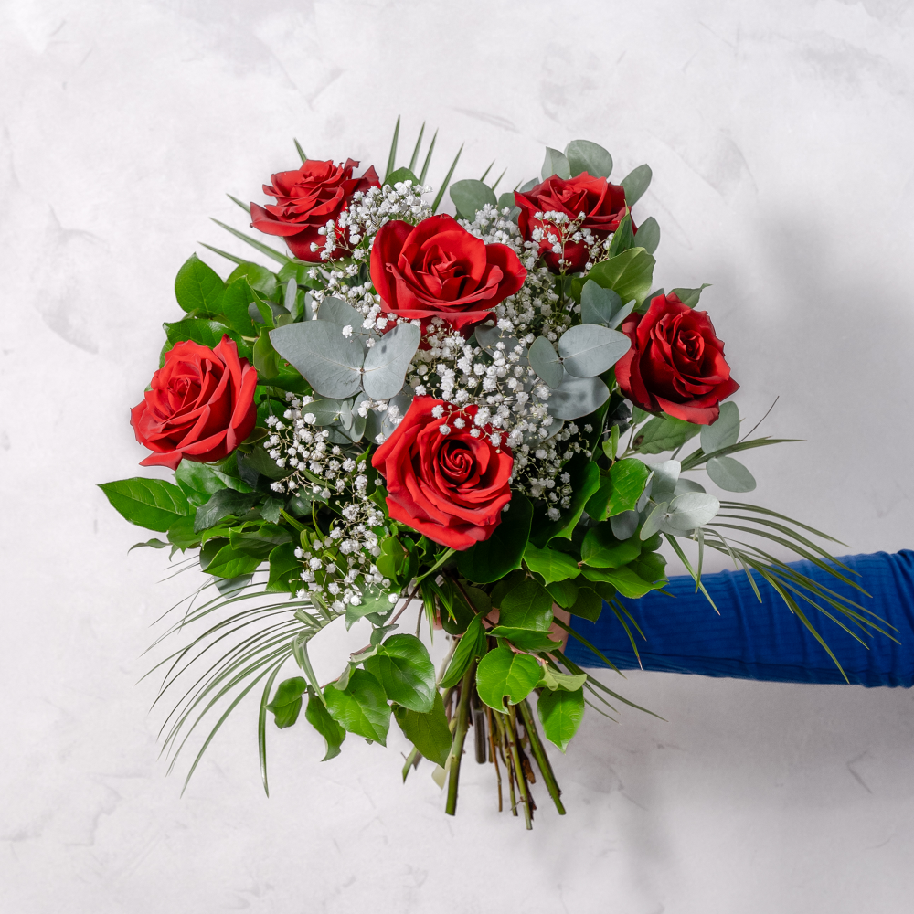 Six deep red premium roses hand-arranged into a classic romantic bouquet, presented with stems wrapped and tied