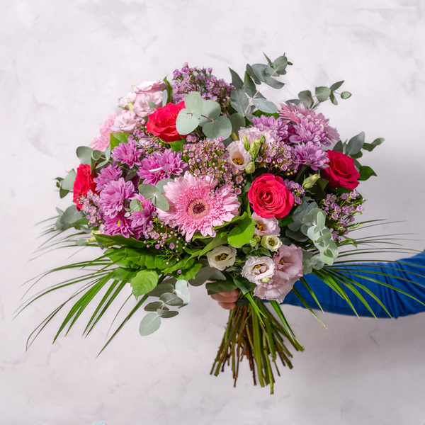 Pretty in Pink bouquet held upright showing red roses gerbera and chrysanthemums