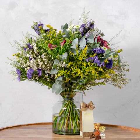Bouquet of flowers in a glass vase on a wooden table with a white background